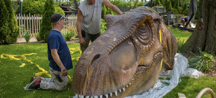 A worker assembles the head of an animatronic dinosaur.