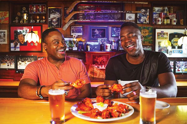 Two men eating wings at Nine-Eleven Tavern bar in Buffalo, New York (photo by Drew Brown)