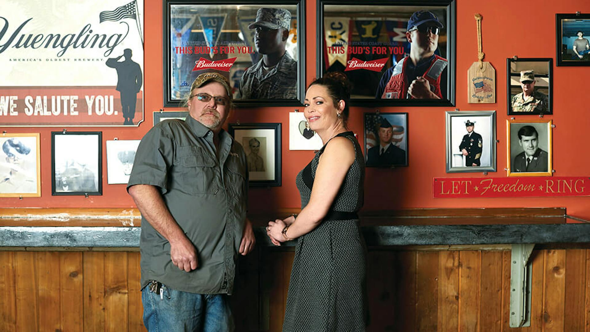 Peeper's Owners in front of Wall of Honor