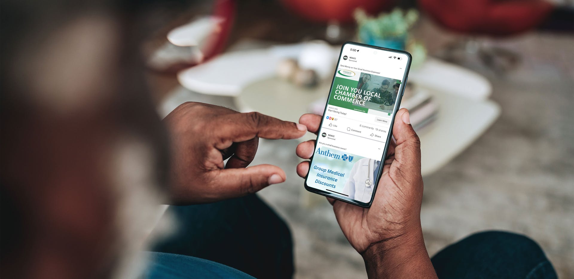 A man's hands holding a phone displaying NOACC Facebook ads