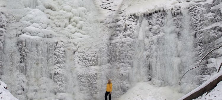 Jeri McMinn stands at the bottom of a huge ice formation.