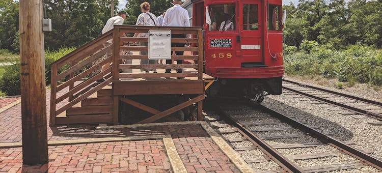 People standing on train platform next to red trolley car at Fox River Trolley Museum in South Elgin, Illinois (photo courtesy of Fox River Trolley Museum)