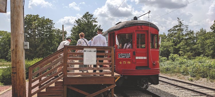 People standing on train platform next to red trolley car at Fox River Trolley Museum in South Elgin, Illinois (photo courtesy of Fox River Trolley Museum)