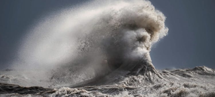 A crashing wave takes the form of a man's face.