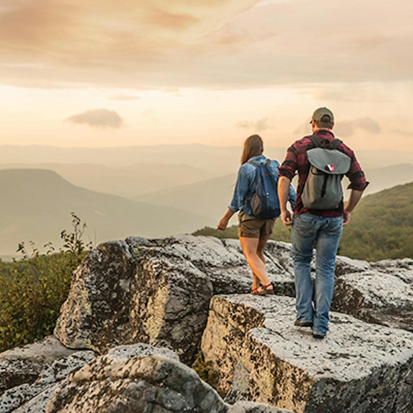 People hiking on rock overlooking mountains in Dolly Sods Wilderness in Davis, West Virginia (photo courtesy of West Virginia Department of Tourism))