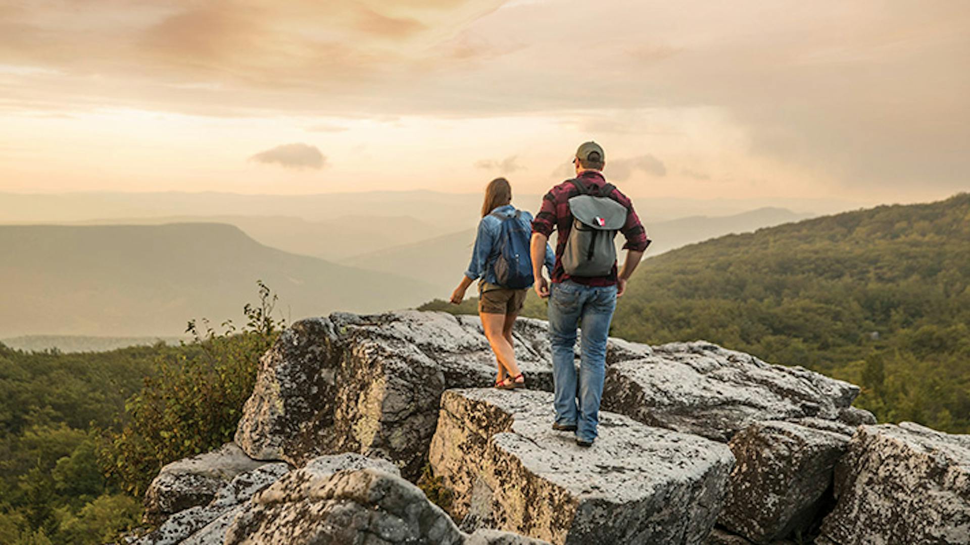 People hiking on rock overlooking mountains in Dolly Sods Wilderness in Davis, West Virginia (photo courtesy of West Virginia Department of Tourism)
